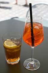Verre de spritz et verre de thé glacé sur une table