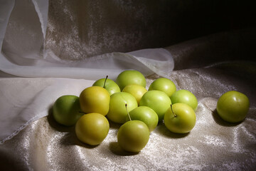 Yellow plums laid out on mother-of-pearl fabric