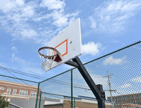 Basketball hoop with chain link fence and blue sky