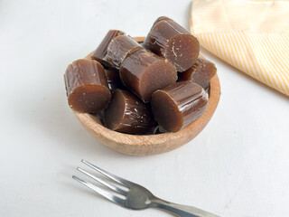 Pieces of glossy brown dodol are arranged in small wooden bowls, showcasing the chewy texture and...