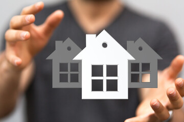 Image of a real estate agent's hands holding three house icons, symbolizing home ownership and...