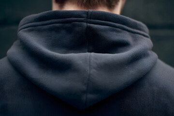 Hooded Silhouette: A detailed, close-up shot of a person wearing a dark hoodie, showcasing the texture and form of the garment, with focus on the hood's design. 