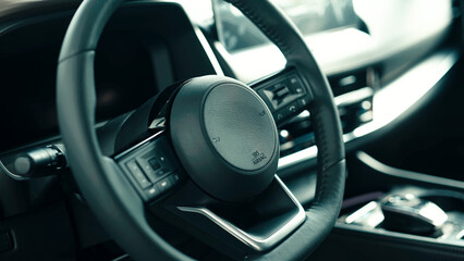 Close-up view of modern car steering wheel showcasing sleek design and high-tech features,...