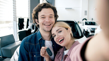 Happy couple celebrating new car purchase in a modern showroom, showcasing excitement and joy in a vibrant automotive environment