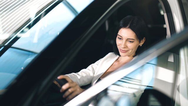 Woman exploring features of a new car in a showroom, showcasing modern design and technology.