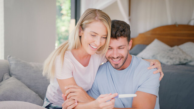 Excited Couple In Bedroom At Home Celebrating Positive Pregnancy Test Result