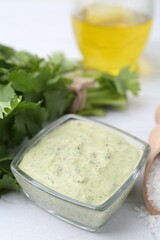 Tasty cilantro sauce in bowl and salt on light textured table, closeup