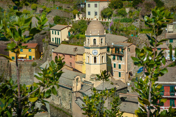 Picturesque view of the church bell tower with clock, town among the hills of Vernazza in Cinque...
