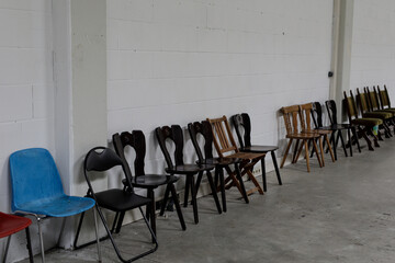 Row of various chairs against a white wall.  Perfect for waiting room, meeting, or office concepts.