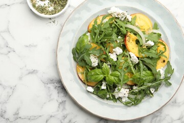 Tasty salad with arugula, cheese, peach, basil and spices on white marble table, flat lay. Space...