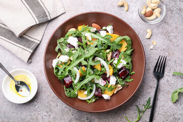 Tasty salad with arugula, cheese, peach, beetroot and nuts on grey table, flat lay