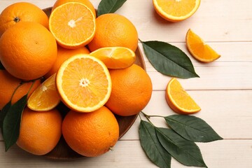 Fresh ripe oranges and leaves on light wooden table, flat lay