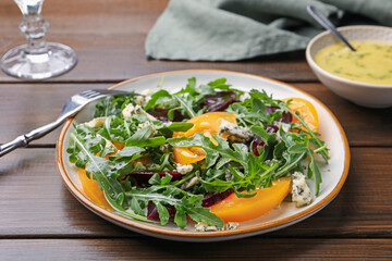 Tasty salad with arugula, blue cheese and vegetables on wooden table, closeup