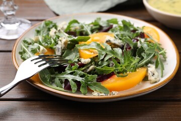 Tasty salad with arugula, blue cheese and vegetables on wooden table, closeup
