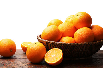 Juicy oranges and wicker basket on wooden table against white background
