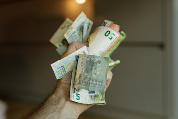 Close-up of a hand holding various euro banknotes and coins.  Financial concept.