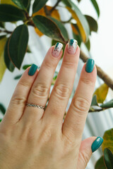 Female hands with green nail design.