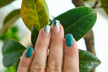 Female hands with green nail design.