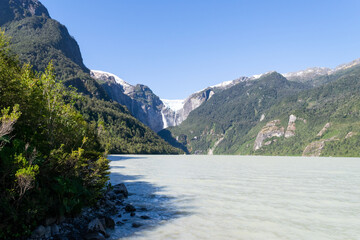 Hanging glacier generating waterfall flowing into grey lake in patagonia chile