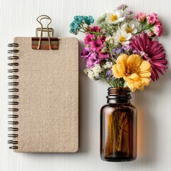 A beautifully arranged bouquet of colorful flowers in a glass jar next to a notebook