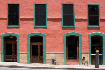Colorful building with salmon pink color walls and  windows and doors  with green borders