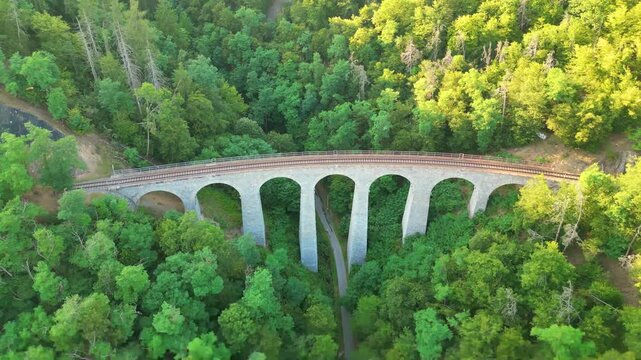 The Zampach railway bridge, the tallest stone bridge in Czechia, showcases its impressive arches surrounded by lush greenery. A breathtaking view of this architectural marvel.