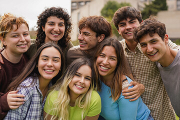 Group of happy students smiling on camera outside of university building - Back to school, campus and lifestyle concept