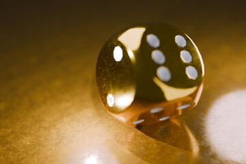 shiny golden die resting on a reflective surface, symbolizing luck, wealth, and chance. Perfect for casino, gambling, gaming, and luxury-themed concepts in advertising and design. Risk, creative idea
