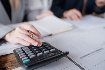 Businesswoman holding a pen and using a calculator, analyzing financial data and preparing reports...