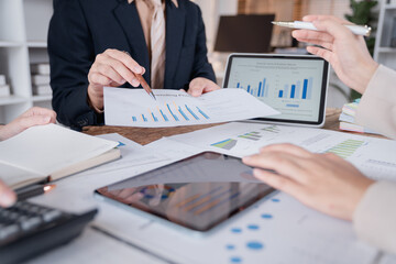 Business team analyzing financial charts and graphs using digital tablet and documents during a...