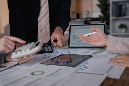 Business team analyzing financial data and using a calculator during a meeting, discussing project planning, market research, and developing strategies for growth