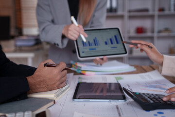 Business team working together, analyzing financial data and company performance using digital tablet and calculator during a meeting in the office