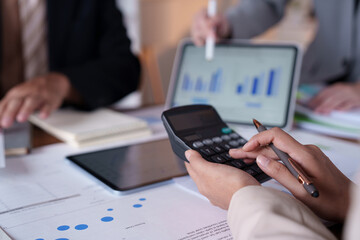 Business team analyzing financial data and utilizing calculators during a meeting, discussing strategies for company growth and planning future investments in a collaborative office setting