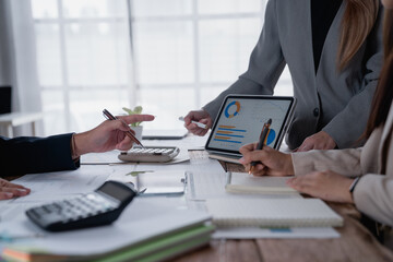 Business people using calculator and digital tablet analyzing sales data and economic growth graph...