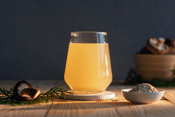 Golden adaptogenic mushroom elixir glows in a modern glass on rustic wood, surrounded by powder and shiitake, radiating natural wellness.