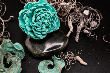Carved turquoise flower with rose-like petals rests on polished labradorite stone against a black...