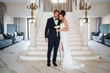 Beautiful and happy bride and groom on a large beautiful staircase.