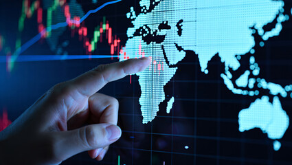 Close up of hand touching Africa on a glowing digital world map with stock charts finance economy