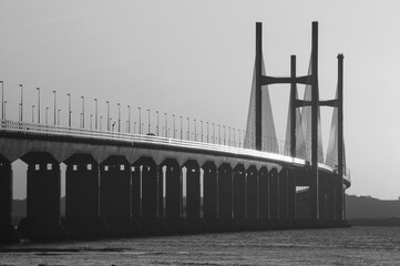 Monochrome image of the Second Severn Crossing with striking symmetry and structural detail, viewed from low angle over calm estuary waters