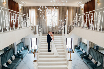Beautiful and happy bride and groom on a large beautiful staircase.