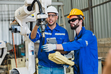 robotics engineers checking a robot arm in an industrial factory