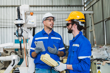 robotics engineers checking a robot arm in an industrial factory