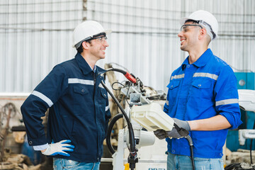 robotics engineers checking a robot arm in an industrial factory