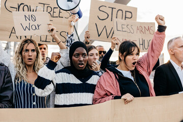 Big organized group of diverse people demonstrating in favor of world peace. Young and senior people united protesting in city street against war, holding antiwar banners and posters.