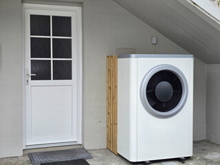 A modern pump heater stands outside a cozy building in the scenic Faroe Islands, Ideal for sustainable heating solutions. Warmte pomp translation: air source heat pump