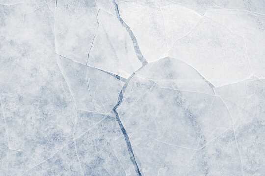 Cracked ice surface background texture with cracks in a light-blue tone.