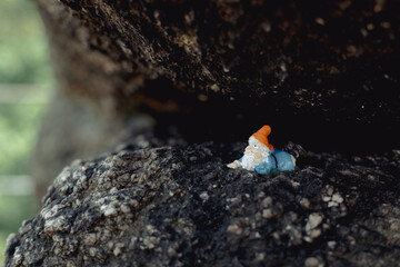 Sokolec Castle, ruins. A plastic dwarf figure lies under a rock, observing the peak opposite. funny trend in Polish mountains