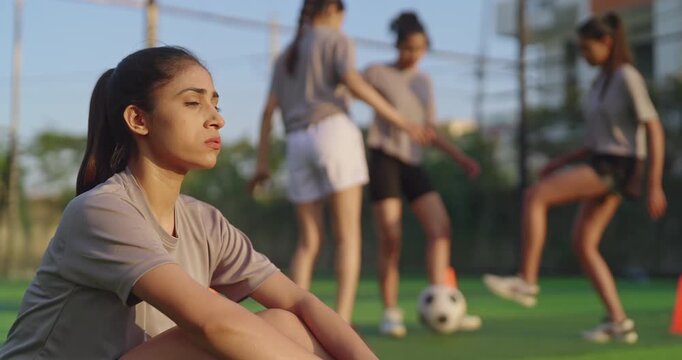 Indian happy athlete woman lady player group play football game kicking soccer ball enjoy team at outdoor yard young adult gen z tired thirsty female girl hold bottle sitting take break drink water - Powered by Adobe