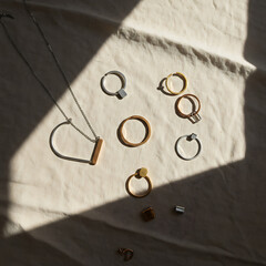 Jewelry collection arranged on a cream-colored fabric, illuminated by sunlight.