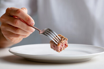 fingers holding fork with lab-grown meat bite over elegant plate, minimal style, 